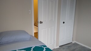 A bedroom with a bed, a white door, and a light switch on the wall.