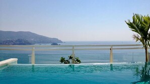 A clear blue pool with a white railing, overlooking a calm sea and distant hills. - The Great Escape - Ixtapa - Penthouse on the Beach (Ixtapa Zihuatanejo)