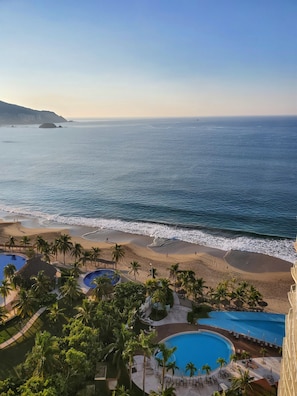 A beach resort with a pool, palm trees, and ocean views.