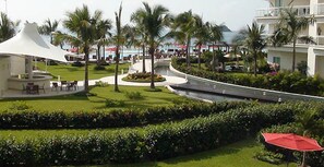 A landscaped area with palm trees, a white tent-like structure, and a curved pathway. - The Great Escape - Ixtapa - Penthouse on the Beach (Ixtapa Zihuatanejo)