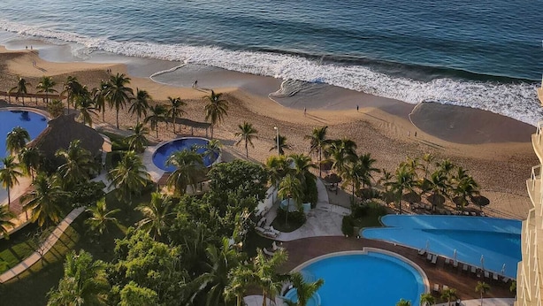 A resort with a beach, a pool, and palm trees. - The Great Escape - Ixtapa - Penthouse on the Beach (Ixtapa Zihuatanejo)
