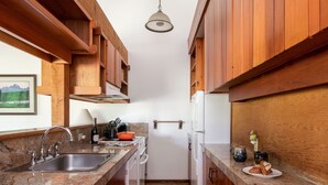 Una cucina angusta con mobili in legno, un piano di lavoro in granito, un lavello e un frigorifero.