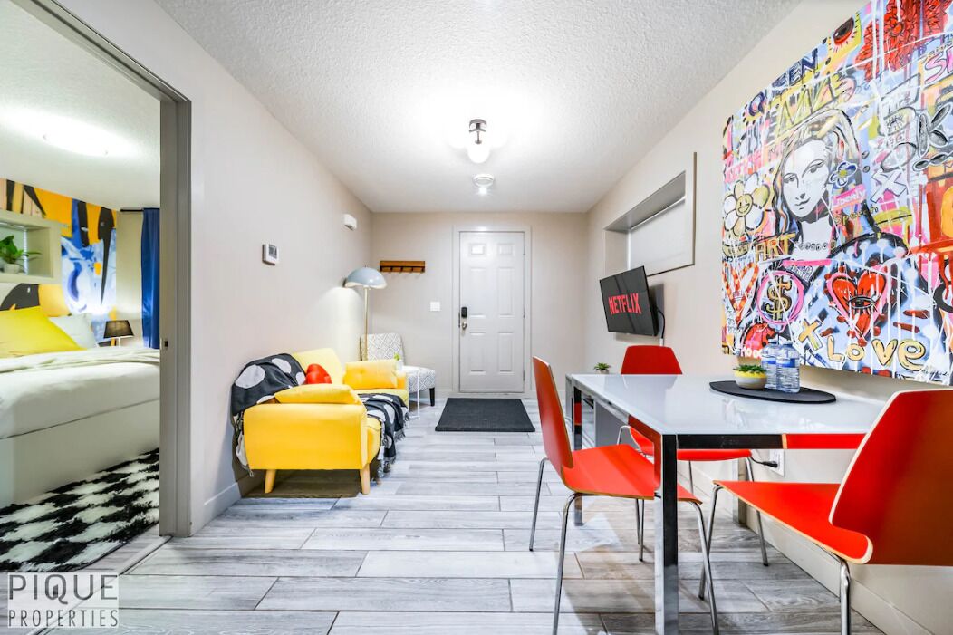 A compact living space with a dining area, a TV, and a colorful graffiti wall.
