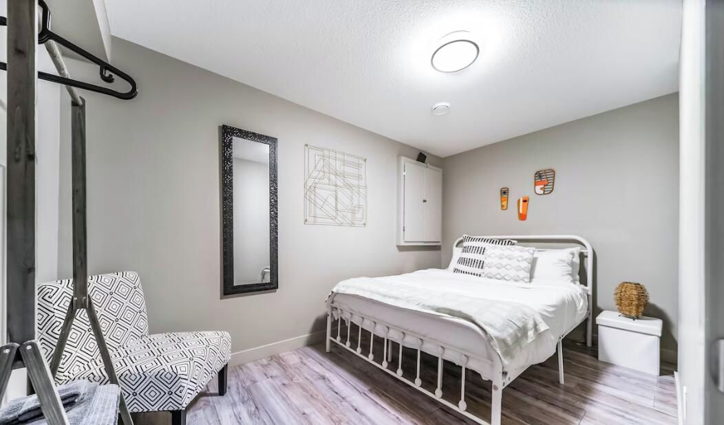 A bedroom with a bed, a chair, a wardrobe, and a mirror.