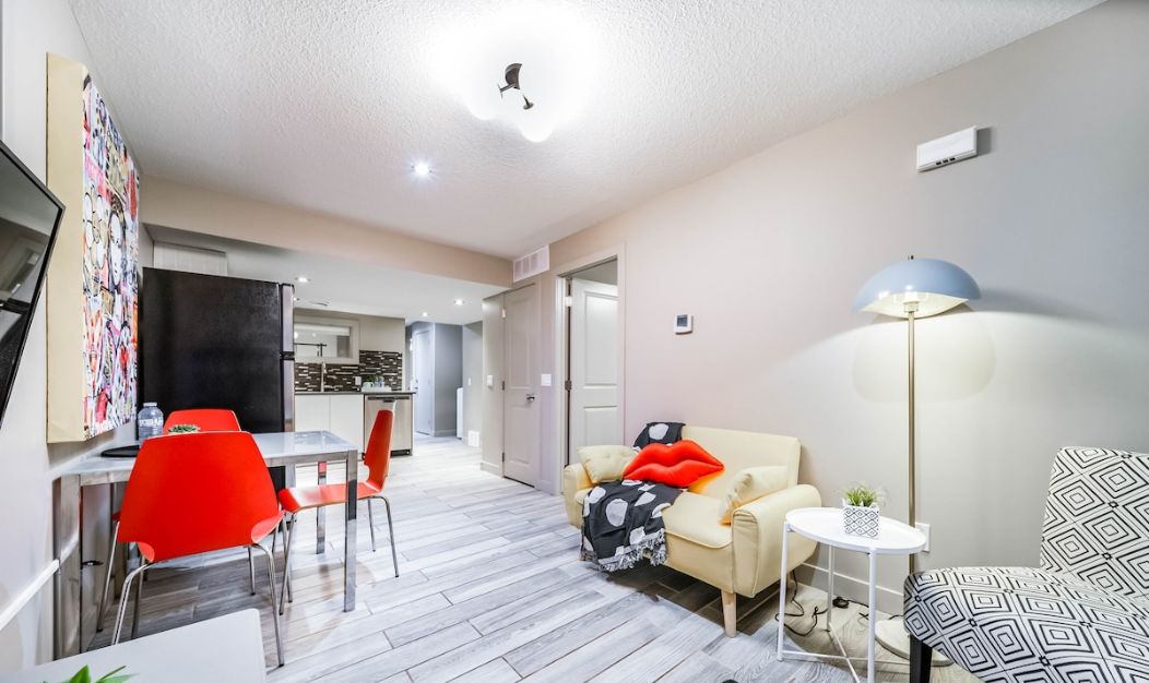 Um apartamento moderno com área de jantar, sala de estar com sofá e poltronas, e cozinha ao fundo.