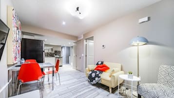 Um apartamento moderno com área de jantar, sala de estar com sofá e poltronas, e cozinha ao fundo.