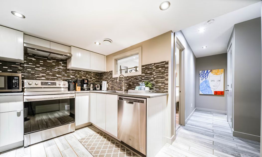 Una cocina moderna con electrodomésticos de acero inoxidable, lavavajillas y salpicadero de azulejos.