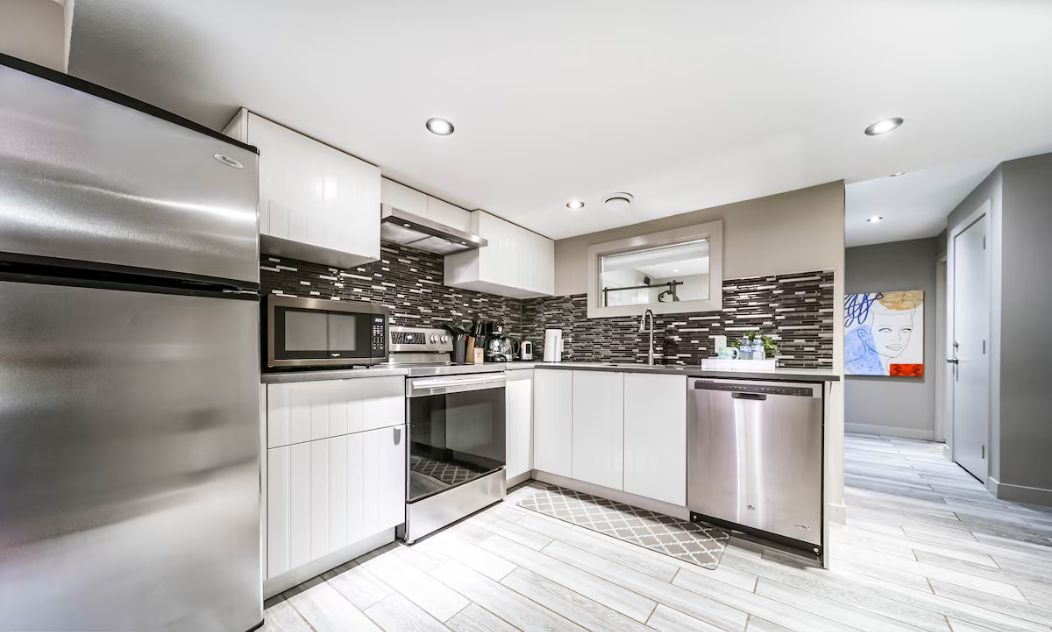 Una cocina moderna con electrodomésticos de acero inoxidable, armarios blancos y un salpicadero con diseño.