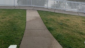 Un parque brumoso con valla de piquetes blancos, un camino y una masa de agua.