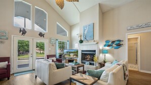 Un salón amplio con chimenea, ventanas grandes y vistas al exterior.