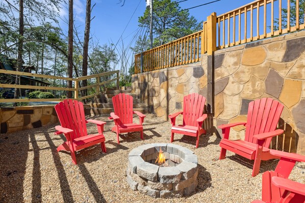 Un muro de piedra con una chimenea y sillas Adirondack rojas.