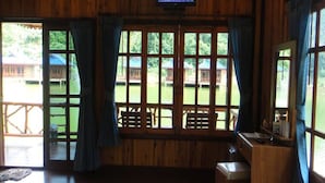 A wooden cabin with large windows, a television mounted above the windows, and a small table with chairs. - Blue Resort and Spa Koh Chang (Ko Chang)
