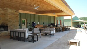 Une terrasse extérieure avec des sièges, un barbecue et une cheminée en pierre.