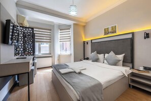 A modern bedroom with a large bed, bedside tables, a desk, and a television. - Taksim Trust Hotel (Istanbul)
