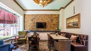 A dining area with a brick wall, a television, a table, and a couch. - Taksim Trust Hotel (Istanbul)