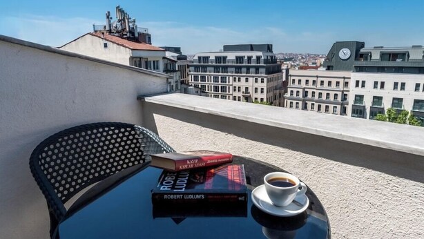 A balcony with a table, a chair, a book titled 'Robert Ludlum's', and a cup of coffee. - Taksim Trust Hotel (Istanbul)