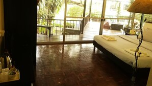 A room with a bed, a bedside table, a lamp, and a view of a balcony with outdoor furniture. - The Hostel 16 (Bangkok)