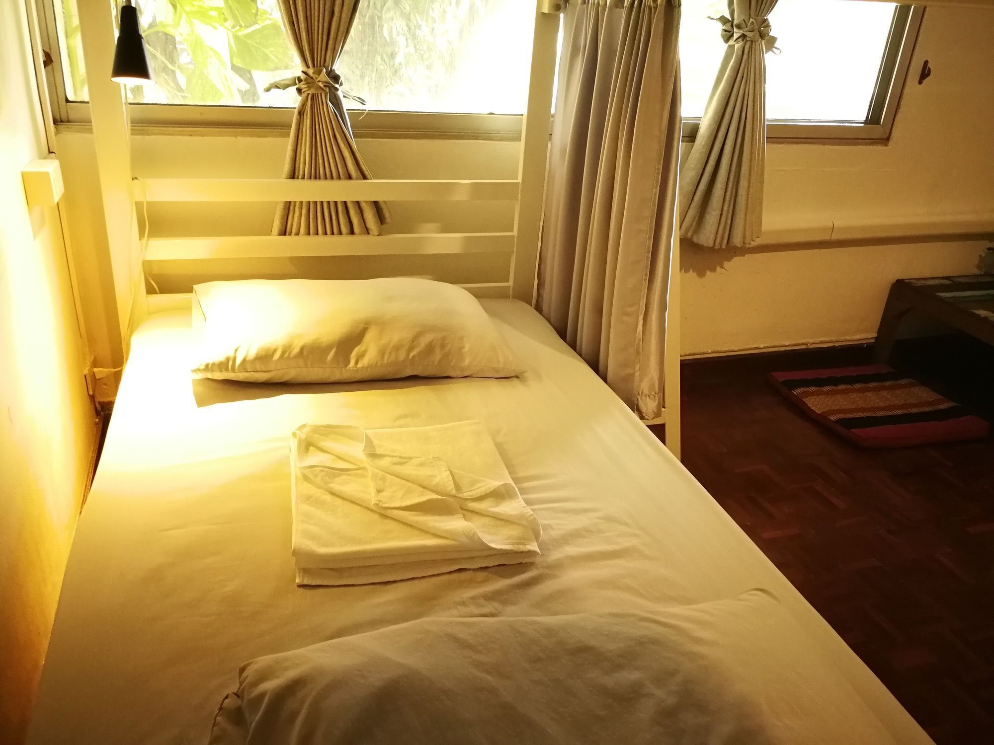 A bed with white linens, a wooden headboard, and curtains tied back at the window.