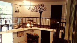 A multi-level living space with a staircase, a ceiling fan, and a wall-mounted tree decoration. - The Hostel 16 (Bangkok)