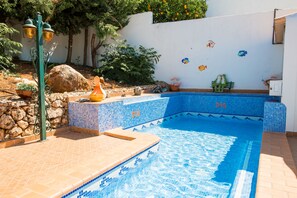 Relax by the serene pool surrounded by lush greenery and a decorative bench.