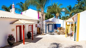 Un patio empedrado con edificios blancos, puertas rojas y una puerta azul.