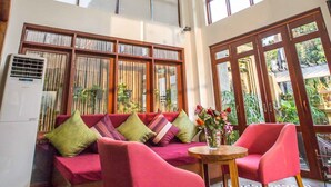 A spacious room with a large window, a ceiling light fixture, and a seating area with a sofa and chairs. - Le Cocon Boutique Hotel (Phnom Penh)