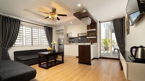 A compact living space with a sofa, a dining table, a kitchenette, and a balcony with a view of the city. - Le Cocon Boutique Hotel (Phnom Penh)