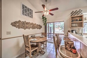 Enjoy meals in this dining area with a round table for four, a ceiling fan, and a decorative wall art piece.