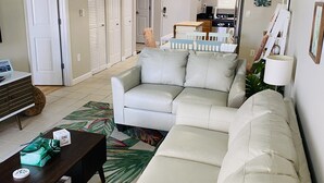 A living room with a beige sofa, a wooden coffee table, and a colorful tropical rug. - Modern Beach Condo ON  St. Pete Beach! (St. Pete Beach)