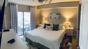 A hotel room with a bed, two bedside lamps, a nightstand, a view of the balcony, and a door. - Modern Beach Condo ON  St. Pete Beach! (St. Pete Beach)