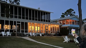 A modern building with large windows and a covered outdoor area with chairs. - The Best Beach-Front House “Get-A-Way” in Florida (Panacea)