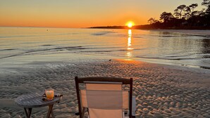 A beach chair and a table with a drink on a sandy beach at sunset. - The Best Beach-Front House “Get-A-Way” in Florida (Panacea)