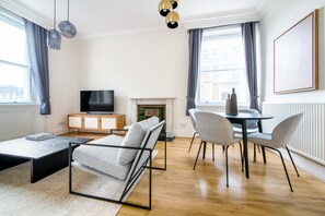 Relax in this stylish living room with a flat-screen TV, comfortable sofa, and dining area by the fireplace.
