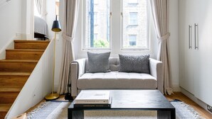 Ein modernes Wohnzimmer mit einer Couch, zwei Kissen, einem Couchtisch und einer Stehlampe.