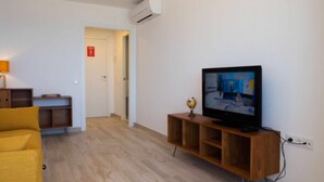 A living room with a television on a wooden stand, a yellow sofa, and a wooden cabinet. - Levante Beach Jazmines Ac (Benidorm)
