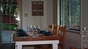 A dining table set with blue bowls and wine glasses, a wooden chair, and a decorative sign on the wall. - Views, good vibes, and vesper skies. (Calistoga)
