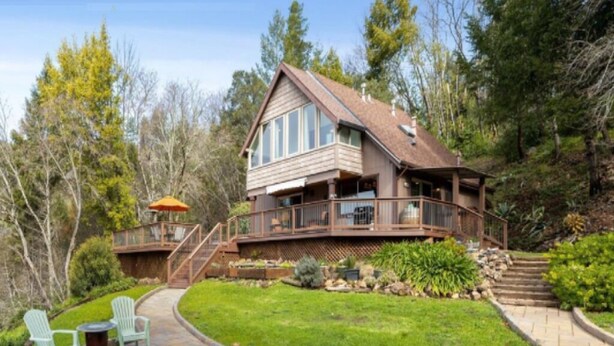 A two-story house with a deck, surrounded by trees and a well-maintained lawn. - Views, good vibes, and vesper skies. (Calistoga)