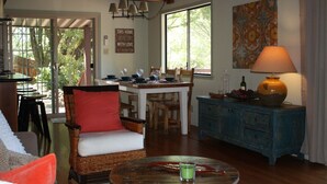 A cozy living room with a wicker chair, a dining table, and a blue cabinet. - Views, good vibes, and vesper skies. (Calistoga)