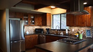 A modern kitchen with wooden cabinets, a stainless steel refrigerator, a microwave, a coffee maker, and a gas stove. - Views, good vibes, and vesper skies. (Calistoga)
