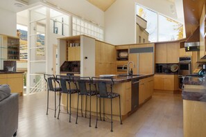 Una cocina moderna con una isla central, taburetes de bar y vistas al exterior.