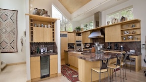A spacious kitchen with wooden cabinets, granite countertops, and a central island with bar stools.