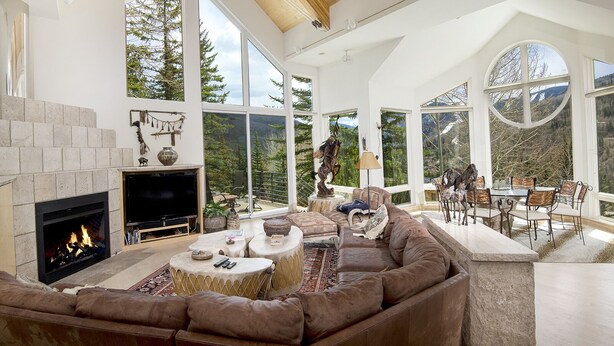 A spacious living room with a fireplace, large windows, and a cozy seating area.