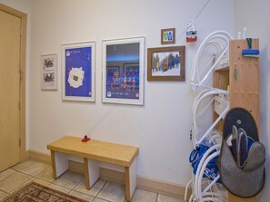 A room with a wooden bench, framed pictures on the wall, and a ski lift model.