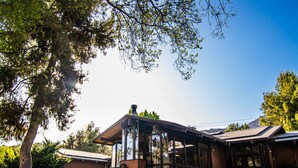 A modern house with large glass windows, a wooden deck, and a well-maintained lawn. - Kaweah River House ~ Private River Access (Three Rivers)