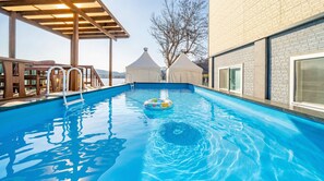 A swimming pool with a floating ring, a wooden deck, and a covered area. - Chuncheon El Dorado Kid's Pension (Chuncheon)