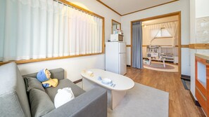 Un espacio habitable compacto con sofá, una mesita, kitchenette y área de juegos para niños.