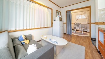 Un espacio habitable compacto con sofá, una mesita, kitchenette y área de juegos para niños.