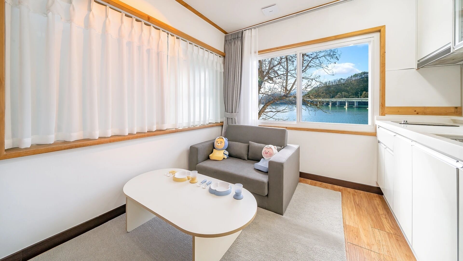 A room with a sofa, a small table, and a view of a bridge over water.