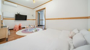 A hotel room with a bed, a TV, a desk with a computer, a chair, and a small play area with toys. - Chuncheon El Dorado Kid's Pension (Chuncheon)
