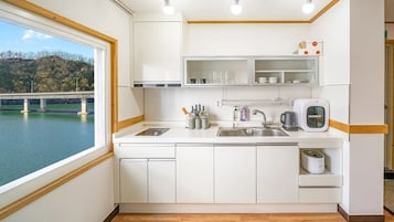 Una cocina moderna con armarios blancos, un lavamanos de acero inoxidable y una cafetera.